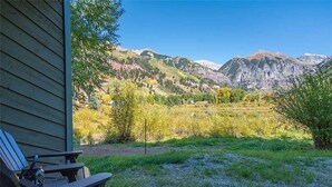 A patio with Adirondack chairs overlooking a mountainous landscape. - Riverside B02 (Telluride)