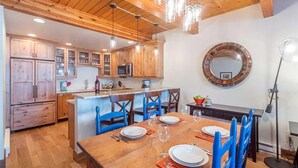 A kitchen with wooden cabinets, a central island, and blue chairs. - Riverside B02 (Telluride)
