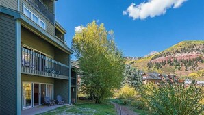 A multi-story building with balconies, a clear sky, and a mountainous backdrop. - Riverside B02 (Telluride)