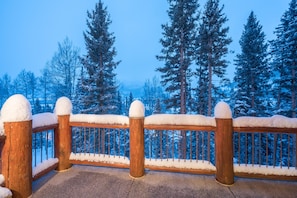 A wooden fence with snow-covered posts and railings, leading to a snowy forest.