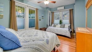A bedroom with two beds, a ceiling fan, and large windows with curtains. - Austin Oasis Near UT and Downtown (Austin)