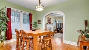 A dining area with a wooden table and chairs, a hanging light fixture, and a view into another room through an archway. - Austin Oasis Near UT and Downtown (Austin)