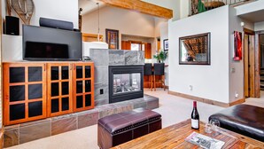 Ein modernes Wohnzimmer mit Kamin, Holzschränken, einem Fernseher und einem Essbereich.