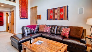 Ein Wohnzimmer mit einer Ledersofa, einem Holztisch und zwei großen Teppichen an den Wänden.