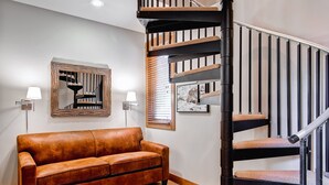 Ein modernes Interieur mit einem braunen Ledersofa, einer Wendeltreppe und zwei Wandleuchten.