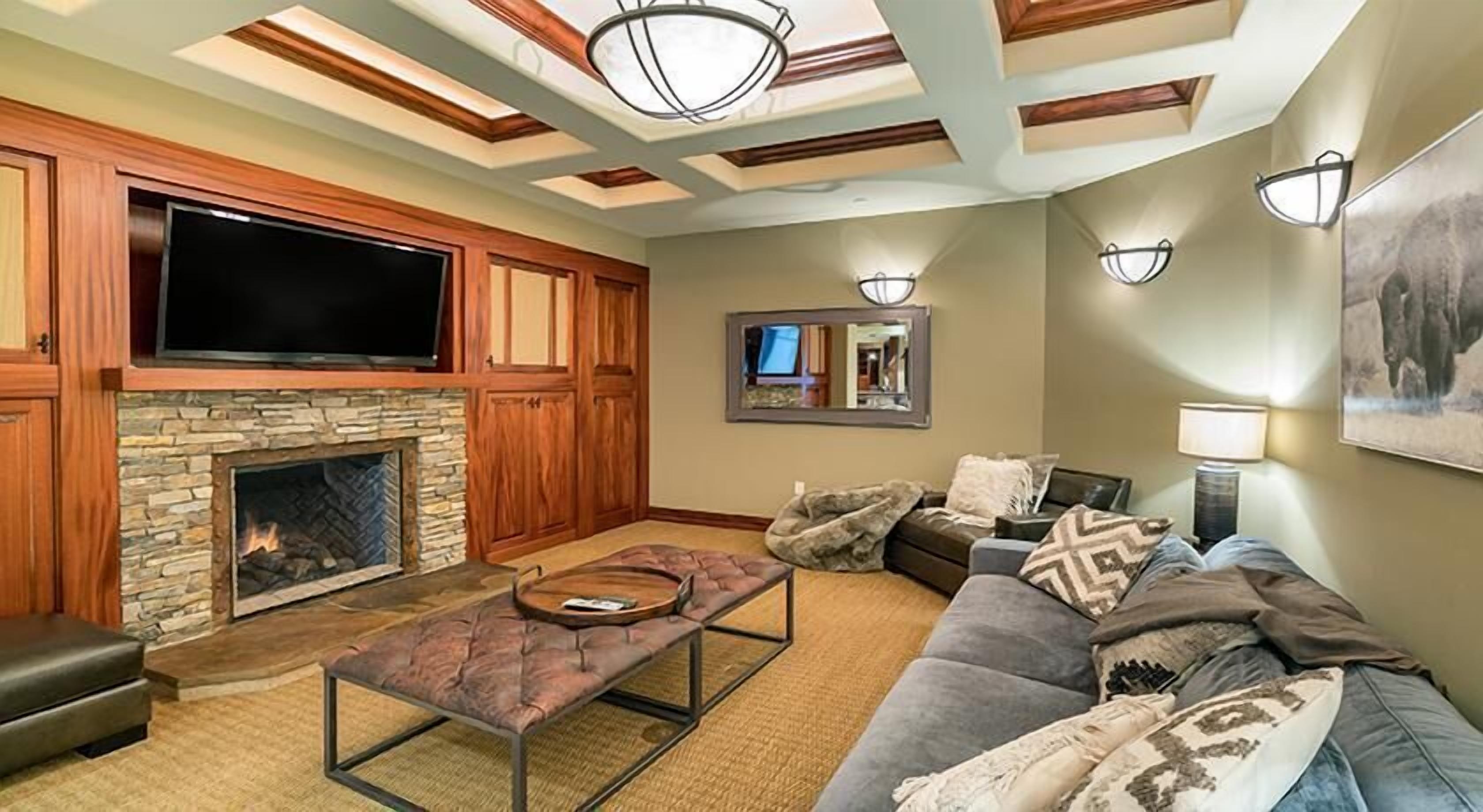 A living room with a stone fireplace, a flat-screen TV, a sofa, and a coffee table.
