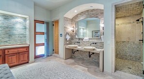A bathroom with two sinks, a large mirror, and a shower area.