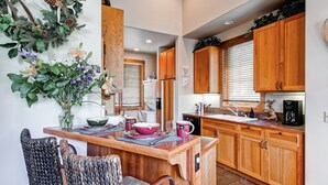 Una cocina con armarios de madera, un comedor con sillas de mimbre y un adorno decorativo en la pared.