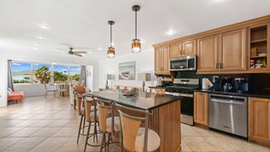 Una cocina moderna con armarios de madera, electrodomésticos de acero inoxidable y una isla grande con taburetes de bar.