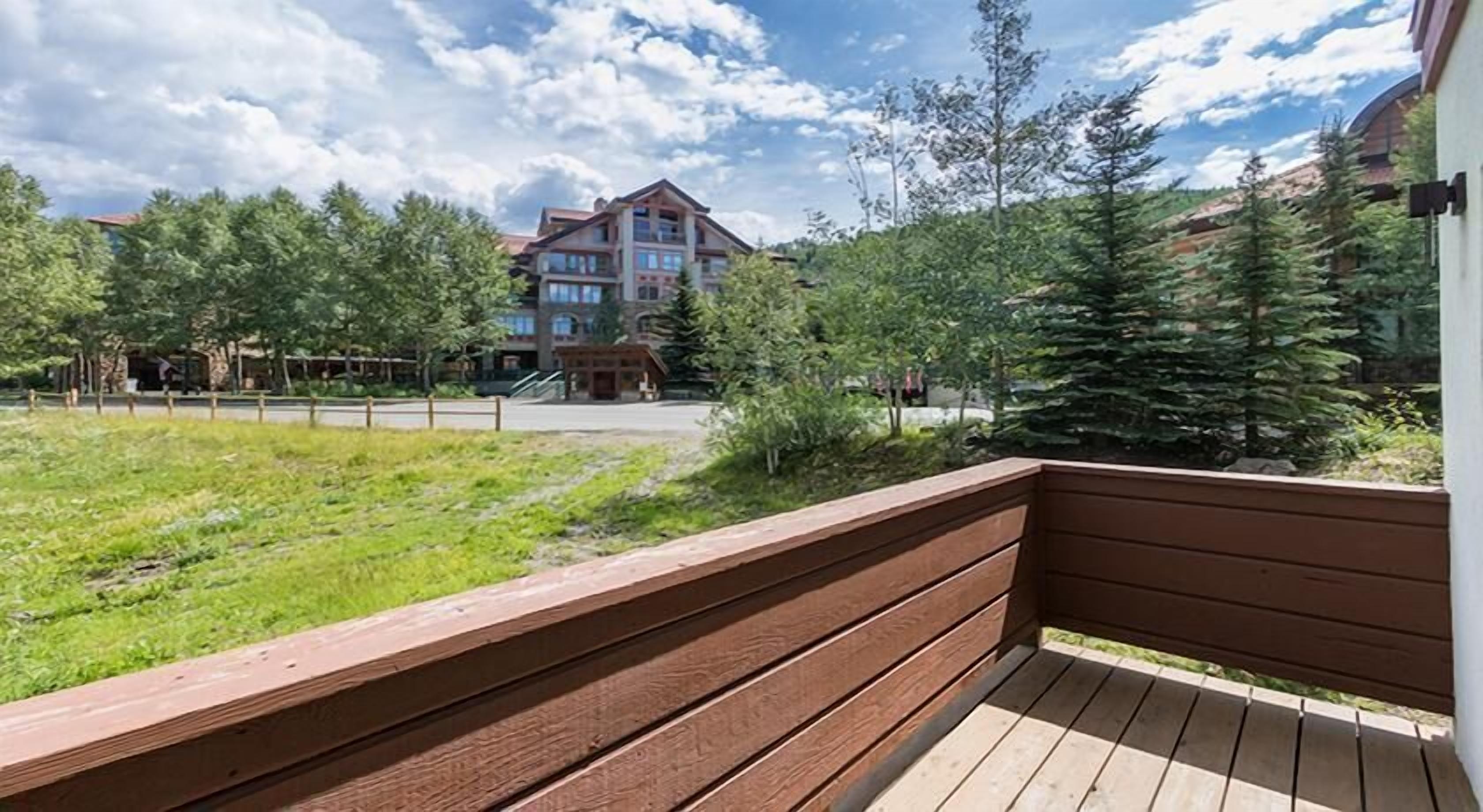 Une terrasse en bois offrant une vue sur un immeuble et des arbres.