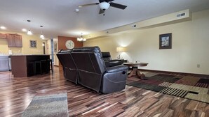 A spacious living area with a leather recliner, a dining table, and a kitchen in the background. - Our Boatyard Loft and Suites Unit A (Sandusky)