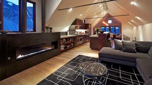 Un espace de vie moderne de style loft, doté d’une cheminée, d’un canapé et d’un coin repas.