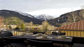 Un coin repas avec une table dressée pour quatre personnes, donnant sur un paysage montagneux.