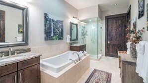 Ein modernes Badezimmer mit einer großen Badewanne, einer Duschkabine aus Glas und einer Holztür.