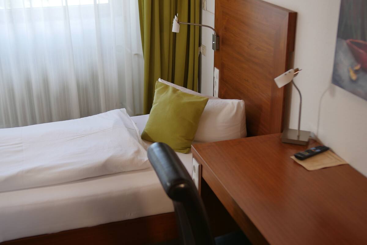 Une chambre d’hôtel avec un lit, un bureau, une chaise, une lampe et un tableau au mur.