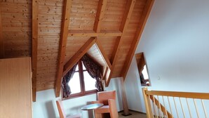 Eine Holzbalkendecke mit einem Fenster und Vorhängen.