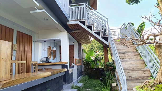 A modern building with a wooden deck, outdoor seating, and a staircase leading to a balcony. - La Montana (Gobleg)