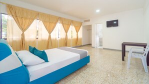 Une chambre d’hôtel avec un lit, des rideaux, une télévision, une table et une chaise.