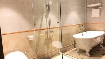 Een badkamer met een douche met glazen wand, een wit toilet en een vrijstaand bad.