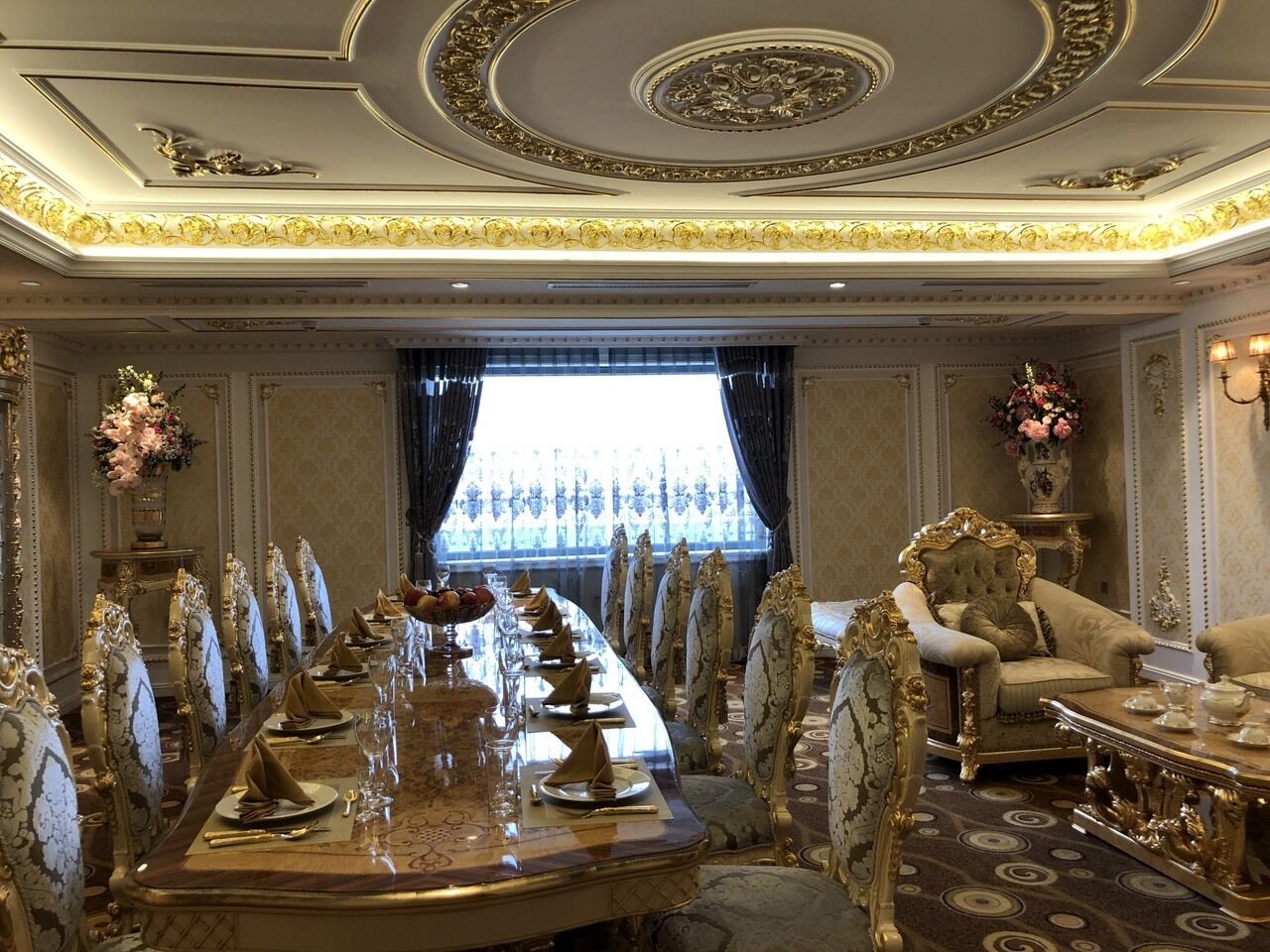 Un comedor formal con una mesa larga, sillas ornamentadas y un sofá lujoso.