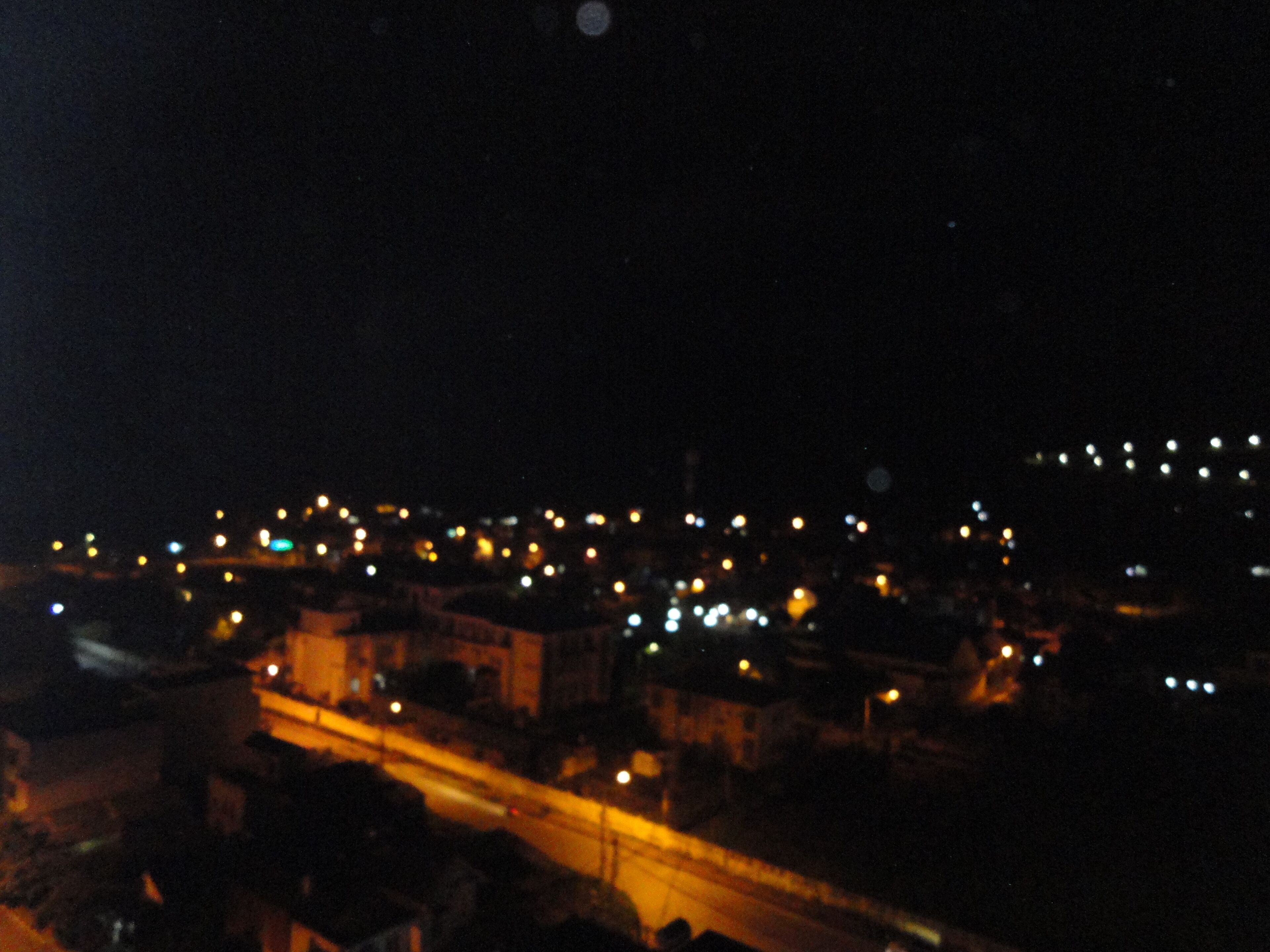 Paisagem urbana noturna com luminárias e edifícios.