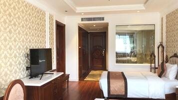 A hotel room with a bed, a desk with a television, a wardrobe, and a large window.