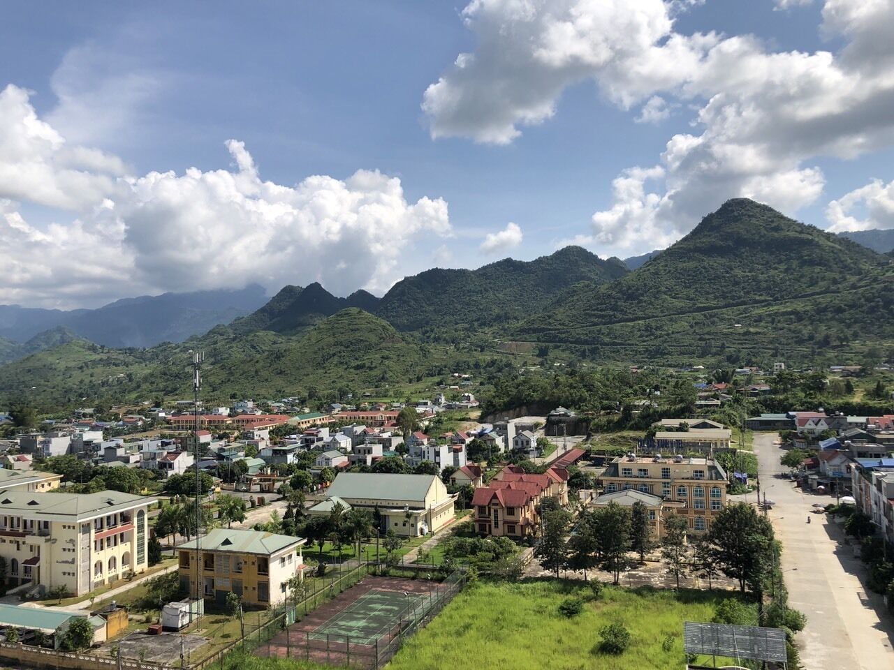 A town with buildings, a sports field, and mountains in the background.