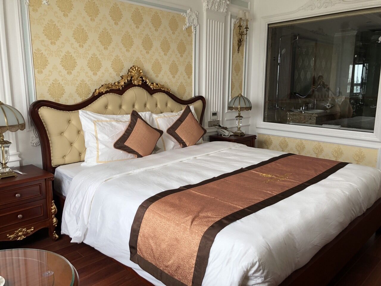 A large bed with a tufted headboard, white bedding, and a brown accent.