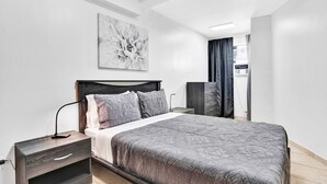 Ein modernes Schlafzimmer mit einem Bett, einem Nachttisch, einer Kommode und einem großen abstrakten Gemälde an der Wand.
