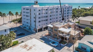 Ein mehrstöckiges Hotel mit Parkplatz, Blick auf den Strand und blauem Himmel.