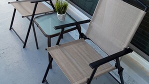 A small outdoor seating area with two chairs and a table, a potted plant, and a view through a window. - Pearl of The Sea, 1 BDRM Condo, 2nd floor, heated pool, 2 min walk to the beach  (Madeira Beach)
