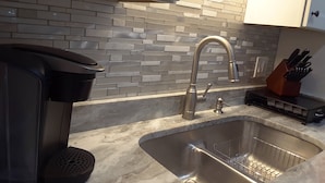A kitchen with a stainless steel sink, a coffee maker, and a knife block. - Pearl of The Sea, 1 BDRM Condo, 2nd floor, heated pool, 2 min walk to the beach  (Madeira Beach)