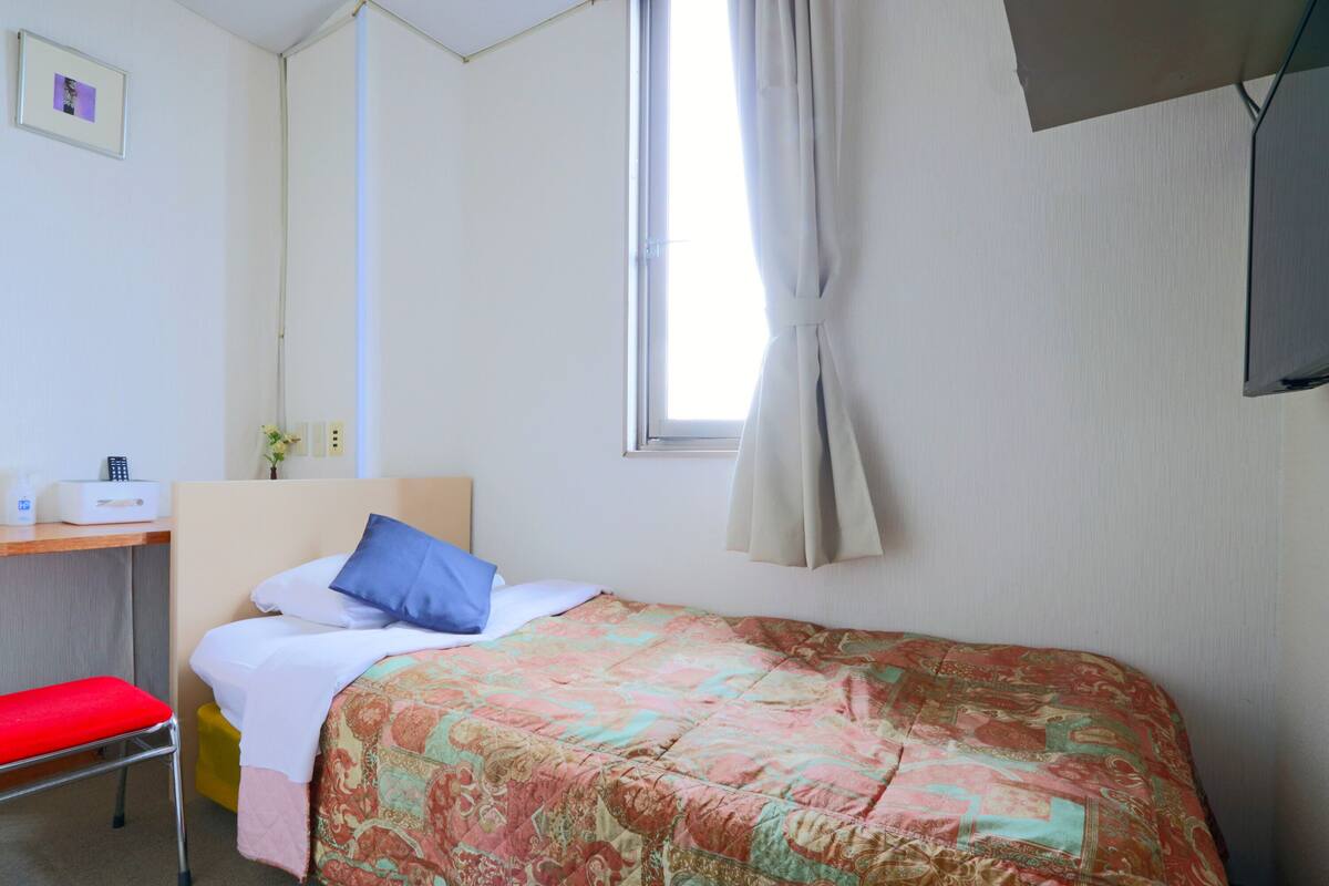 Una habitación de hotel con una cama, un escritorio y una silla.