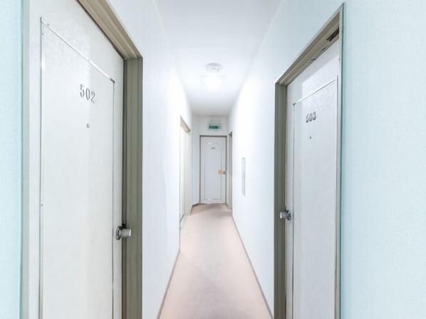 A narrow, well-lit hallway with doors numbered 502 and 503, leading to a door with an emergency exit sign.