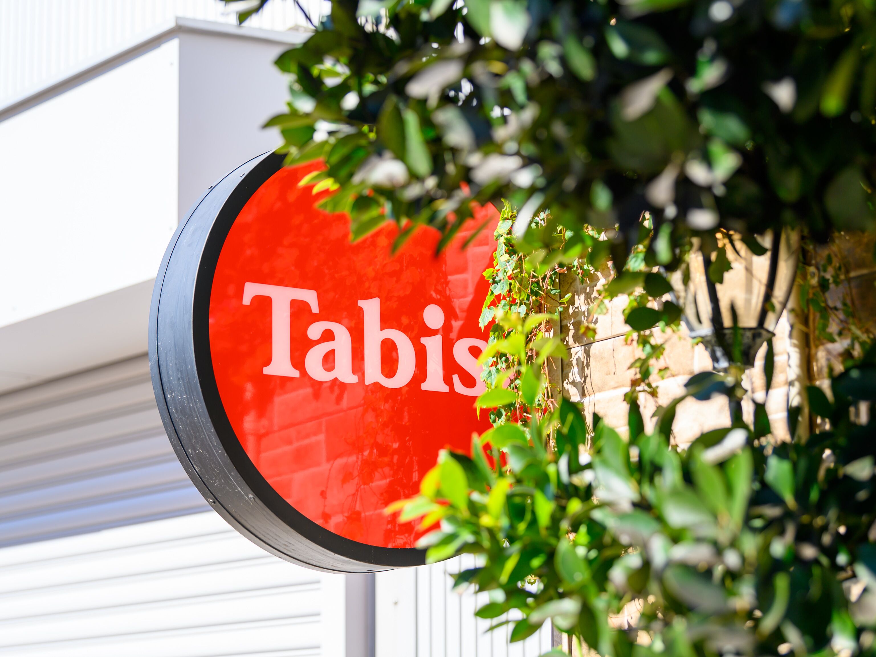 A red sign with the word "Tabis" partially obscured by foliage.