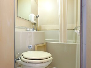 Une petite salle de bain compacte, équipée de toilettes, d’un lavabo et d’une douche.