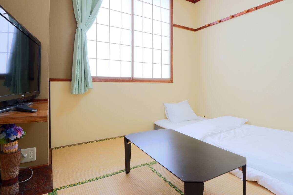 Una habitación con una cama, un televisor y una mesa.
