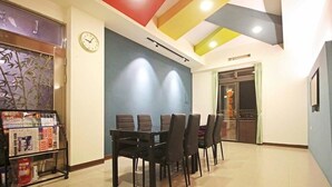 Un comedor con una mesa y sillas, un reloj en la pared y un panel decorativo con plantas.