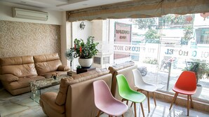 A living room with a brown sofa, a glass coffee table, and colorful chairs. - Tu Phuong Hotel (Ho Chi Minh City)
