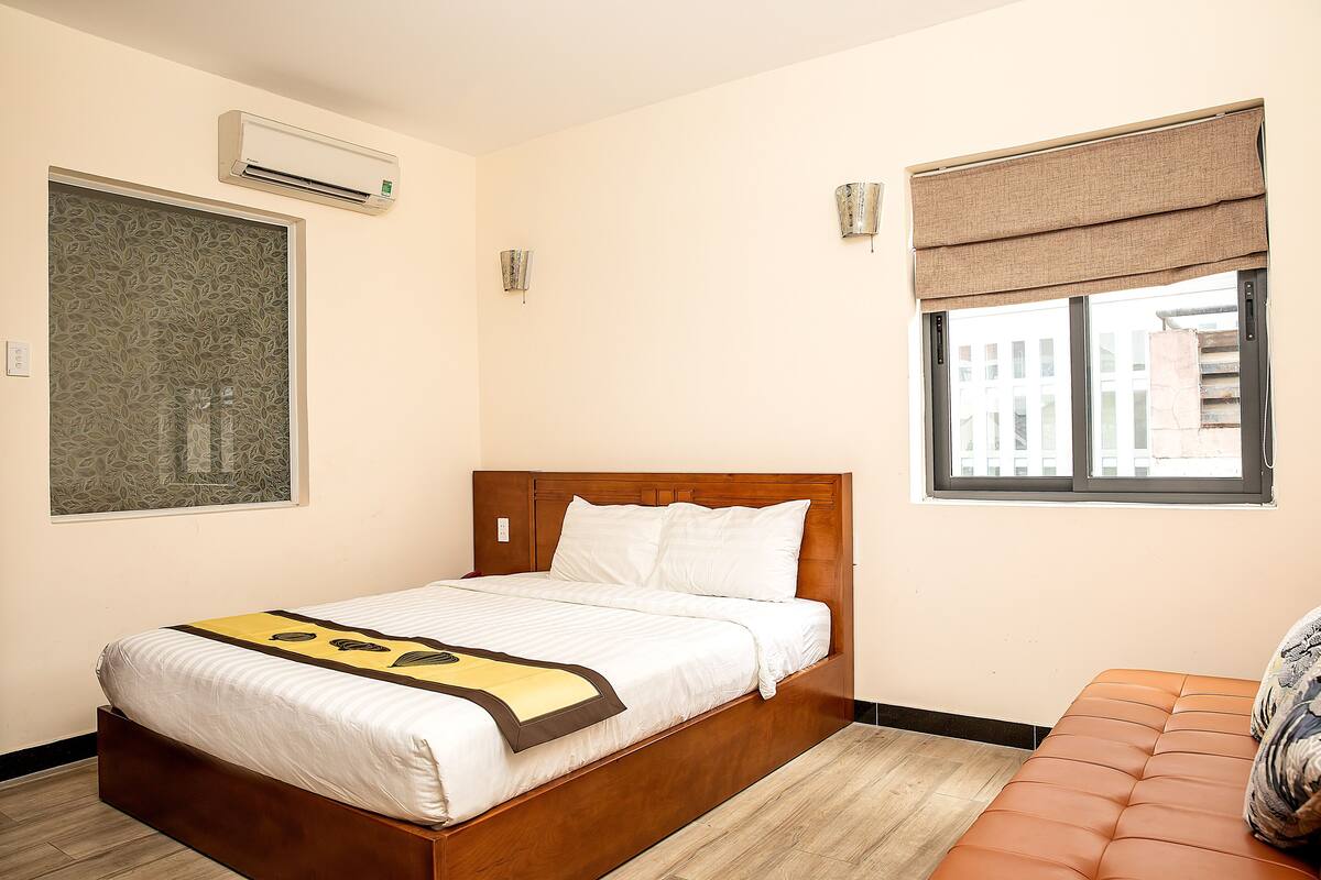 Habitación de hotel con cama, aire acondicionado, ventana con vistas y un cuadro colgado en la pared.