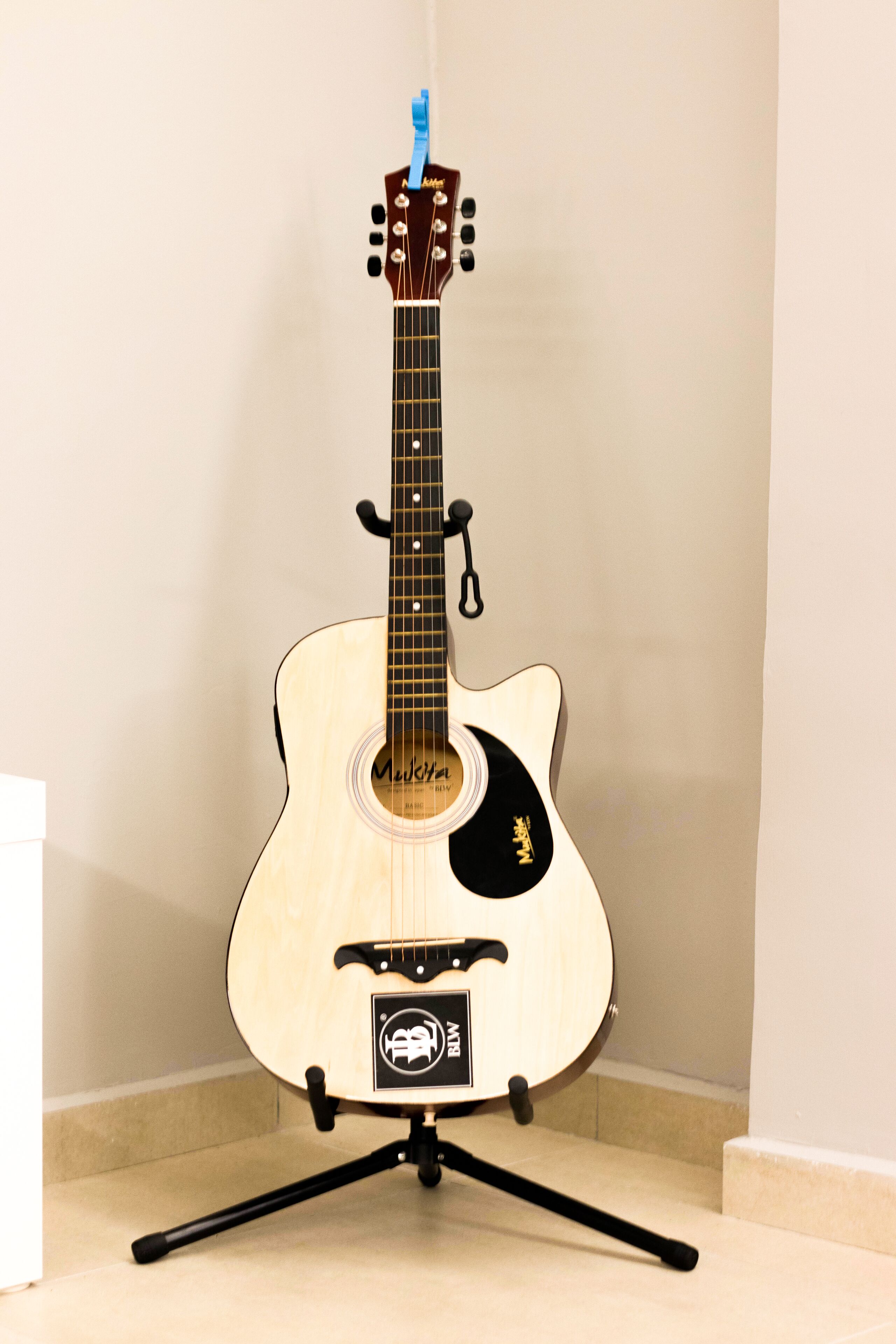 A classical guitar on a stand in a corner.