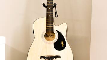 A classical guitar on a stand in a corner.