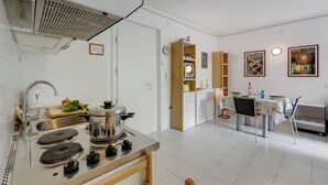 Una cocina moderna con estufa, pileta y comedor con mesa y sillas.