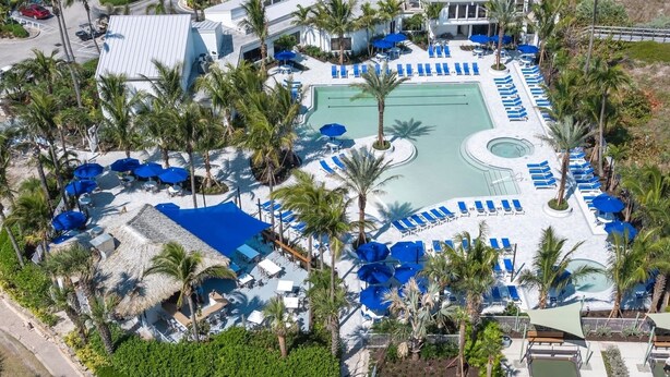 Vista aérea de un resort con varias piscinas, tumbonas y palmeras.