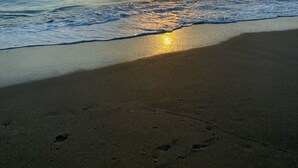 Una playa con un atardecer sobre el océano.