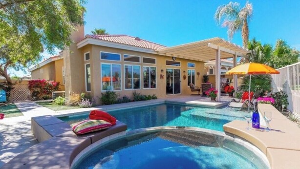 Ein Wohnhaus mit Pool, überdachter Terrasse und angelegtem Garten.