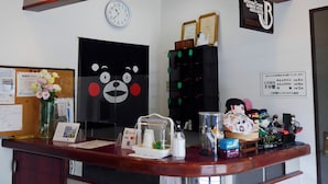 A reception desk with a clock, framed certificates, a bulletin board, a bear-themed decoration, and various items on the counter. - Station Business Hotel Tenshukaku Hitoyoshi (Hitoyoshi)