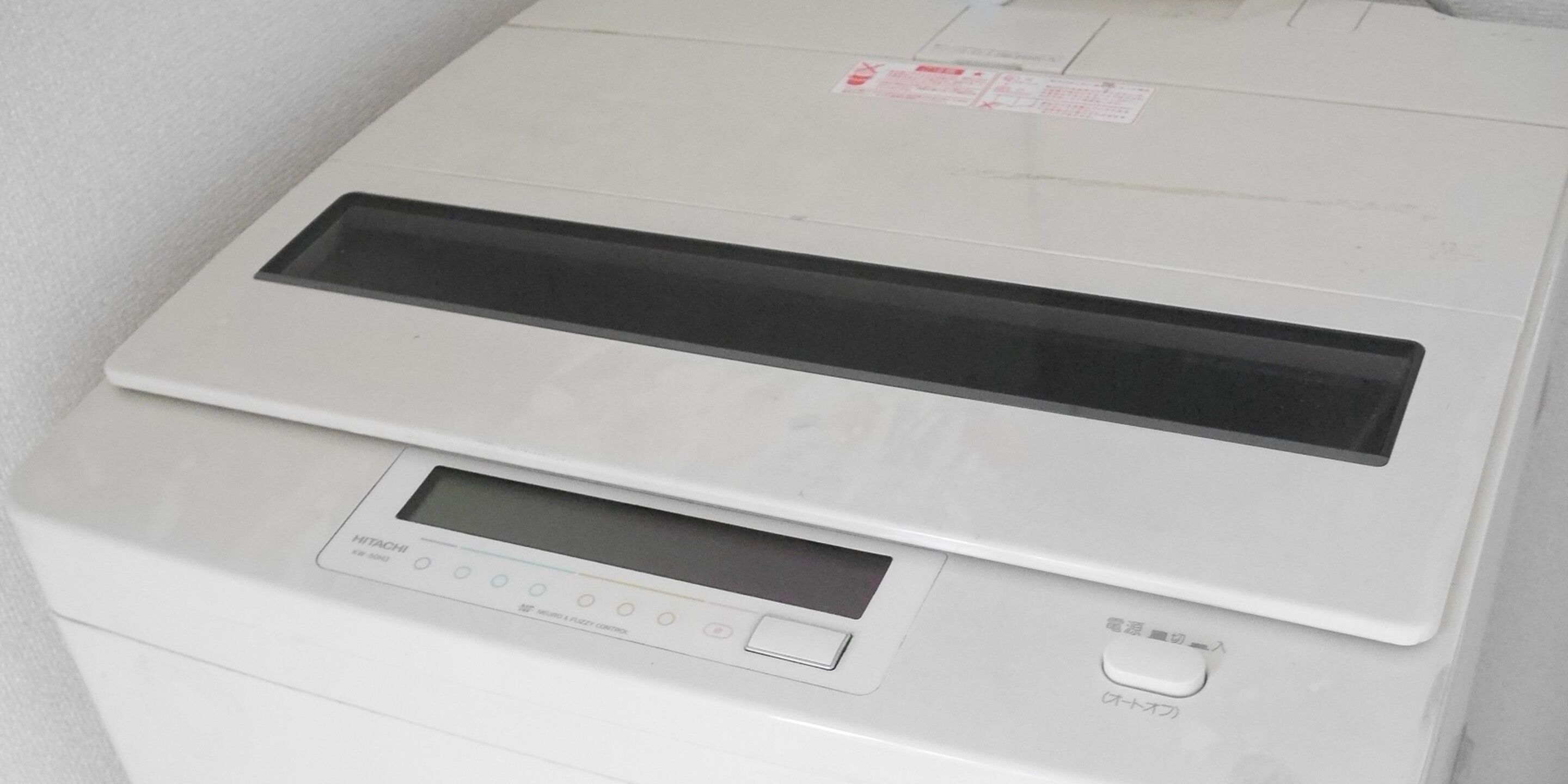 En hvid printer, der står stille, med kontrolpanel og papirbakke.