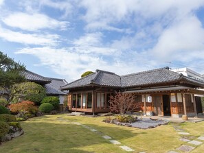 A traditional Japanese house with a tiled roof, a wooden exterior, and a well-maintained garden with stepping stones and shrubs. - Iizukatei (Nakagawa)