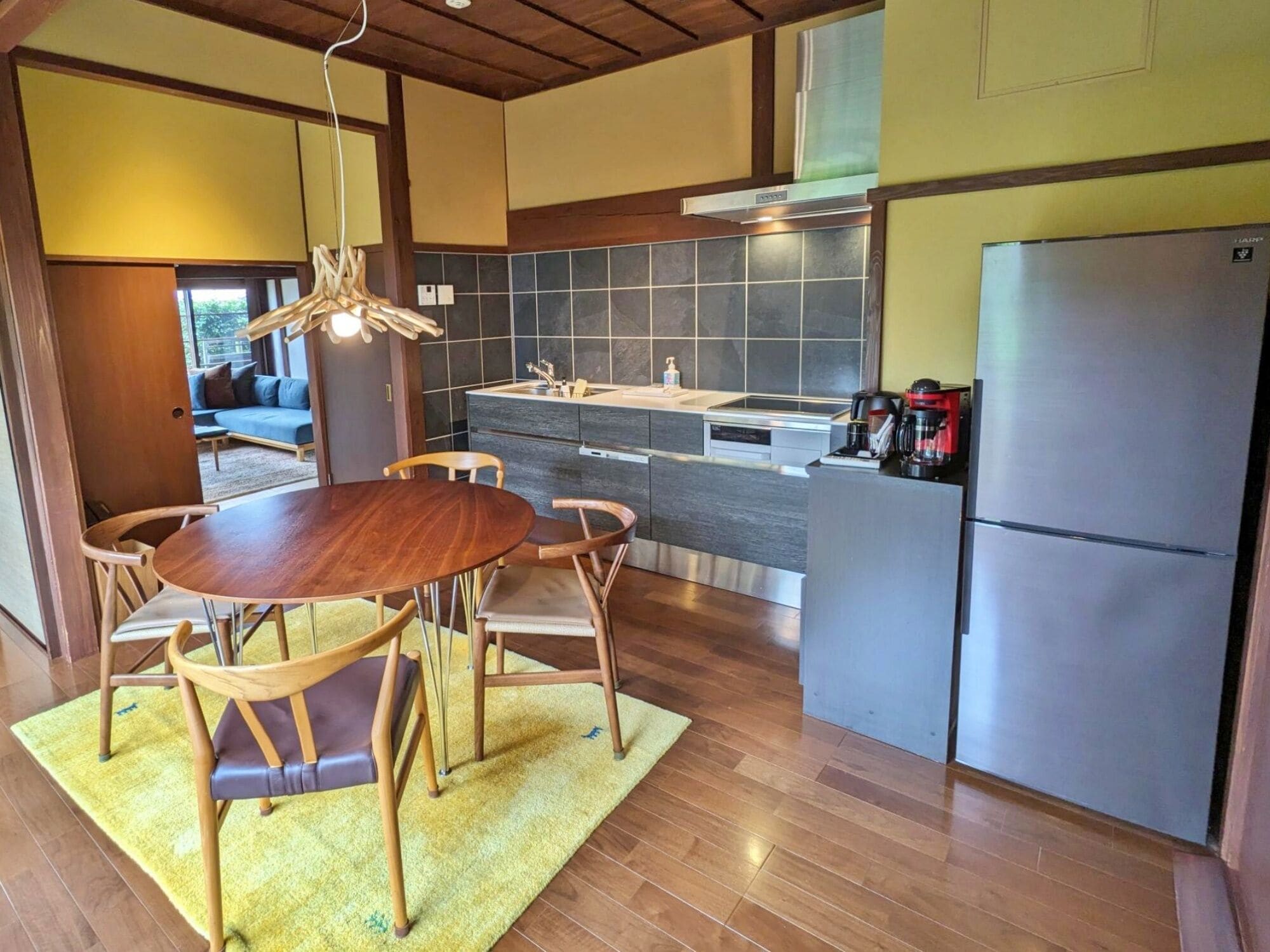 Une cuisine moderne dotée d’un îlot central, d’appareils électroménagers en acier inoxydable et d’un coin repas avec des chaises en bois.